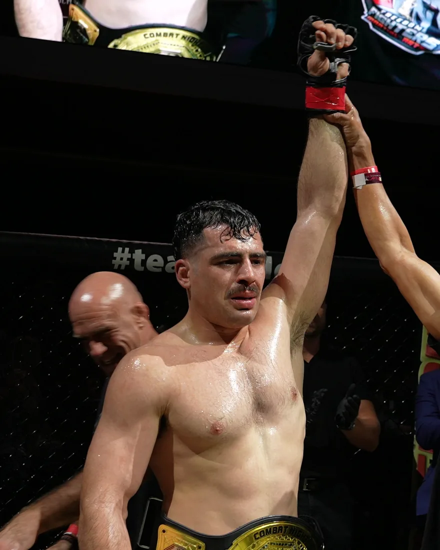 Luis Hernandez with his hand raised and the Combat Night belt around his waist