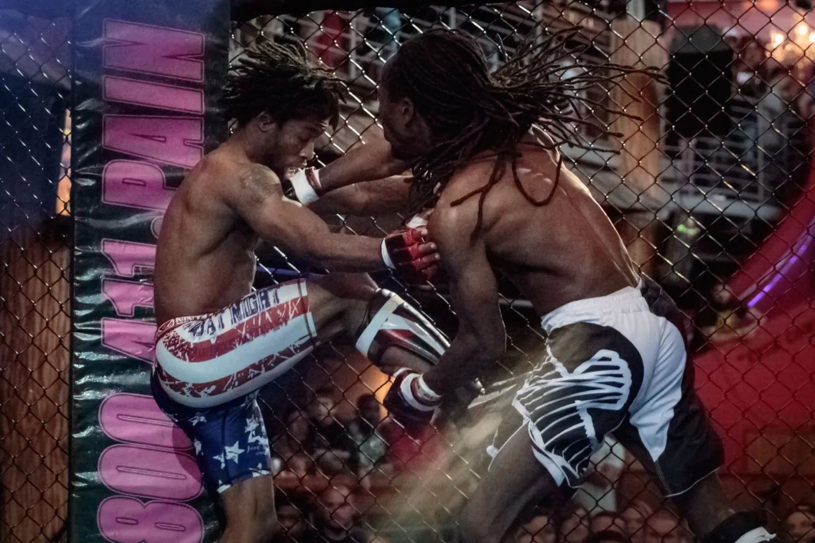 Two Combat Night fighters trading strikes inside the cage